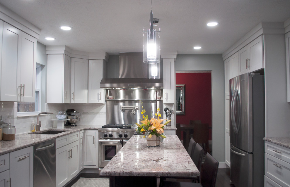 Bild på ett stort funkis kök, med en undermonterad diskho, skåp i shakerstil, vita skåp, granitbänkskiva, vitt stänkskydd, stänkskydd i tunnelbanekakel, rostfria vitvaror, mörkt trägolv och en köksö