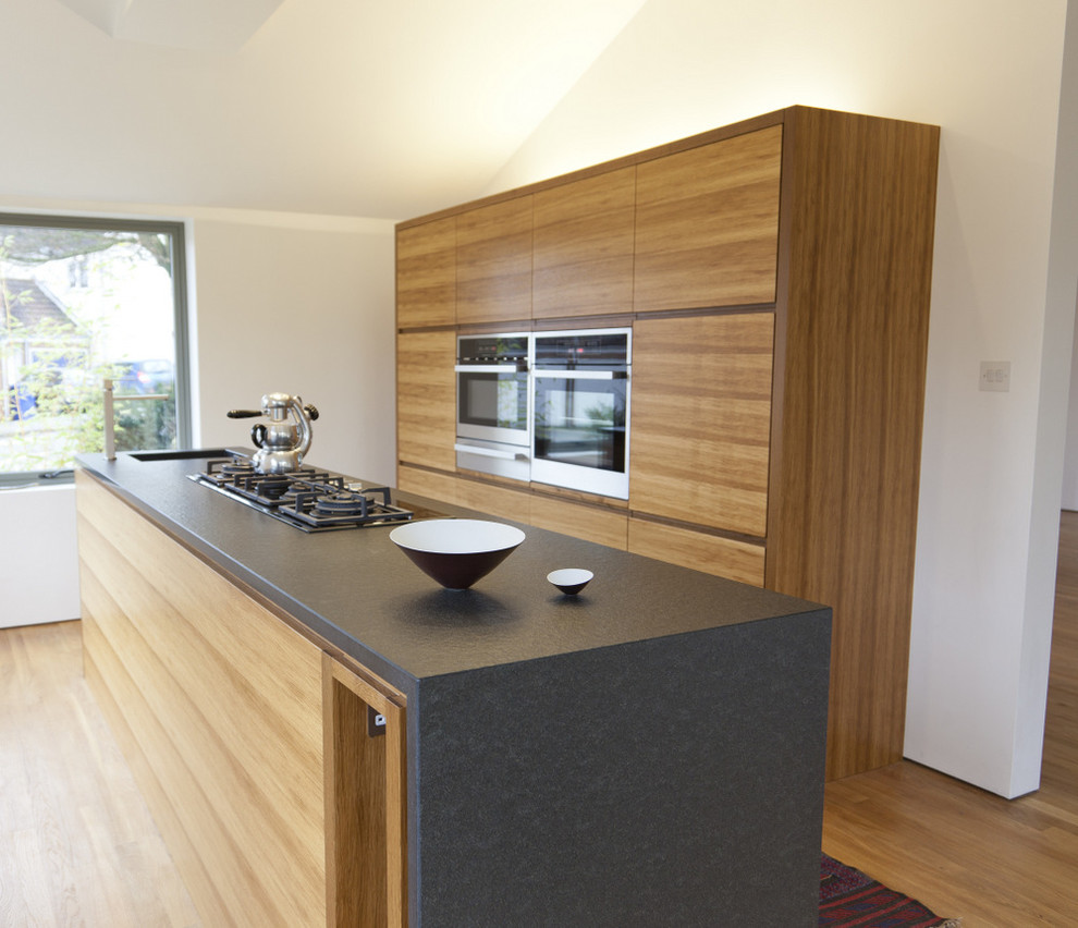 Example of a small trendy galley enclosed kitchen design in London with an undermount sink, medium tone wood cabinets and an island