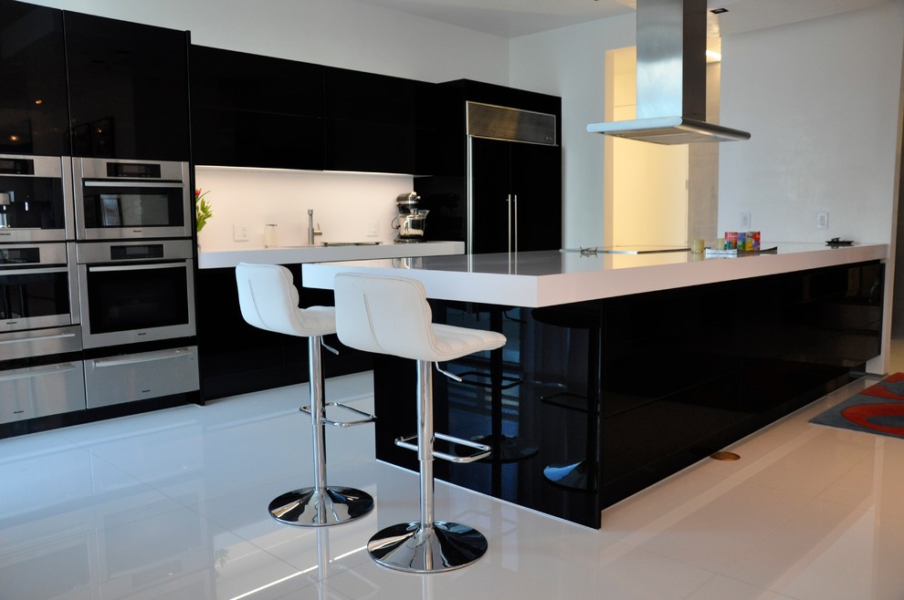 Inspiration for a medium sized modern u-shaped kitchen/diner in Miami with a submerged sink, flat-panel cabinets, black cabinets, engineered stone countertops, white splashback, stone slab splashback, stainless steel appliances, marble flooring and an island.