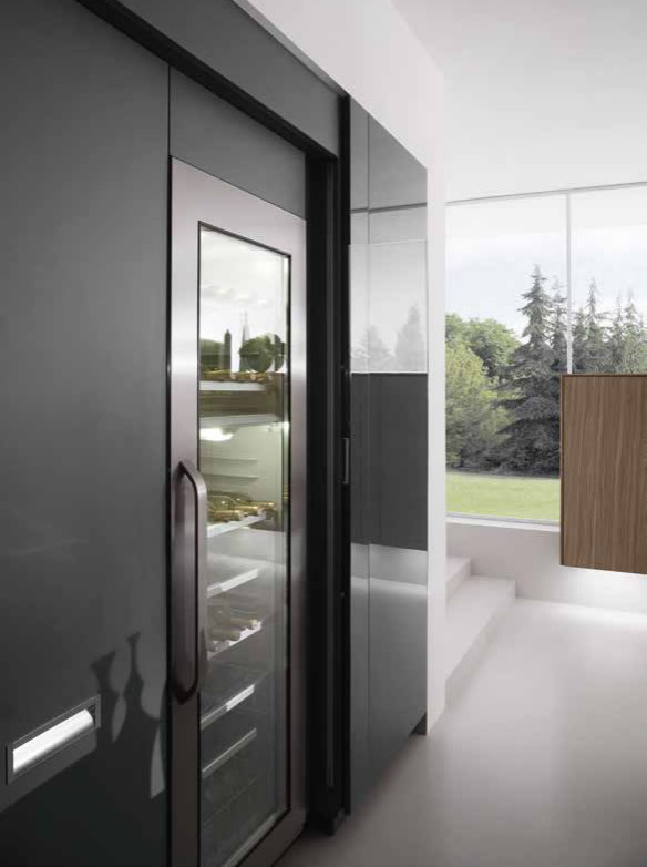 Modelo de cocina moderna grande con armarios con paneles lisos, puertas de armario negras, encimera de acero inoxidable, electrodomésticos de acero inoxidable, una isla y suelo gris