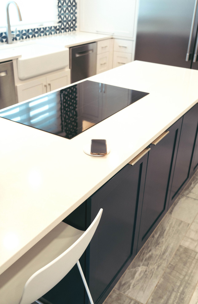 This is an example of a large modern u-shaped kitchen pantry in Other with a belfast sink, shaker cabinets, yellow cabinets, engineered stone countertops, blue splashback, glass tiled splashback, stainless steel appliances, porcelain flooring, an island, grey floors and white worktops.