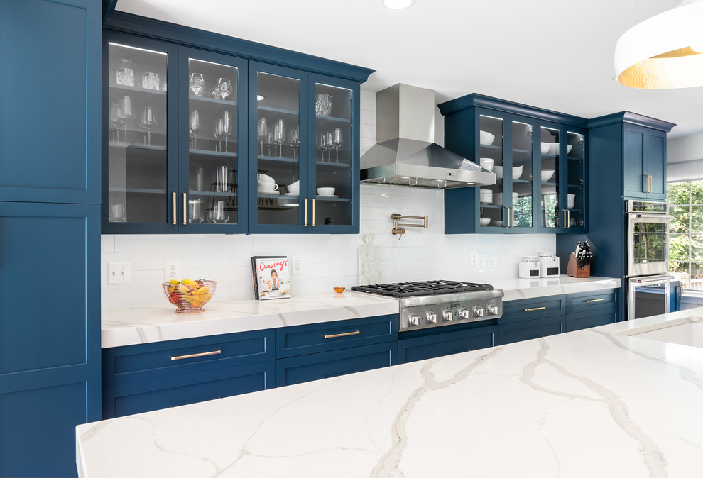 Foto på ett mycket stort funkis vit linjärt kök och matrum, med en undermonterad diskho, luckor med glaspanel, blå skåp, bänkskiva i kvarts, vitt stänkskydd, stänkskydd i keramik, rostfria vitvaror, ljust trägolv, en köksö och beiget golv