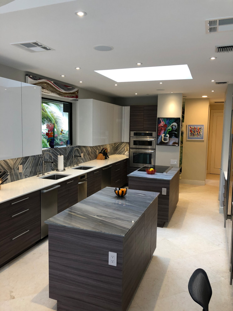 Design ideas for a large modern galley enclosed kitchen in Miami with a submerged sink, flat-panel cabinets, porcelain splashback, stainless steel appliances, limestone flooring, multiple islands and beige floors.