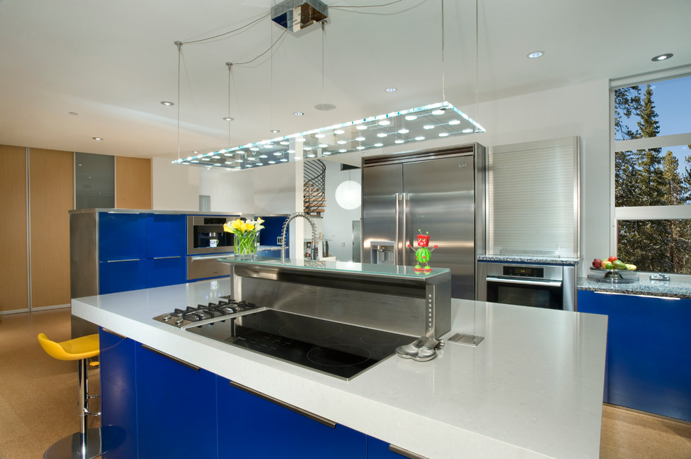 Imagen de cocina minimalista con puertas de armario azules, armarios con paneles lisos y electrodomésticos de acero inoxidable