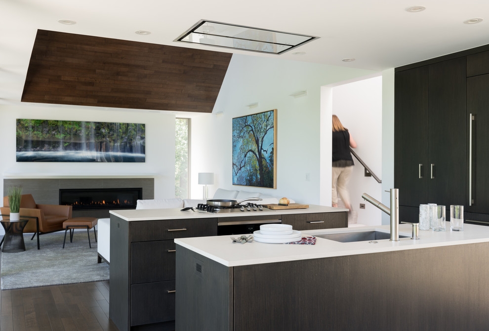 Design ideas for a contemporary open plan kitchen in Denver with a submerged sink, flat-panel cabinets, black cabinets, dark hardwood flooring, multiple islands, brown floors and white worktops.