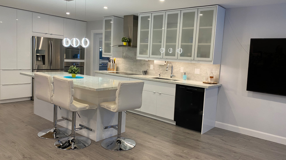 Example of a mid-sized trendy galley laminate floor and gray floor open concept kitchen design in Toronto with an undermount sink, glass-front cabinets, white cabinets, quartz countertops, gray backsplash, porcelain backsplash, stainless steel appliances, an island and multicolored countertops