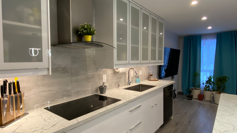 Inspiration for a medium sized contemporary galley open plan kitchen in Toronto with a submerged sink, glass-front cabinets, white cabinets, engineered stone countertops, grey splashback, porcelain splashback, stainless steel appliances, laminate floors, an island, grey floors and multicoloured worktops.