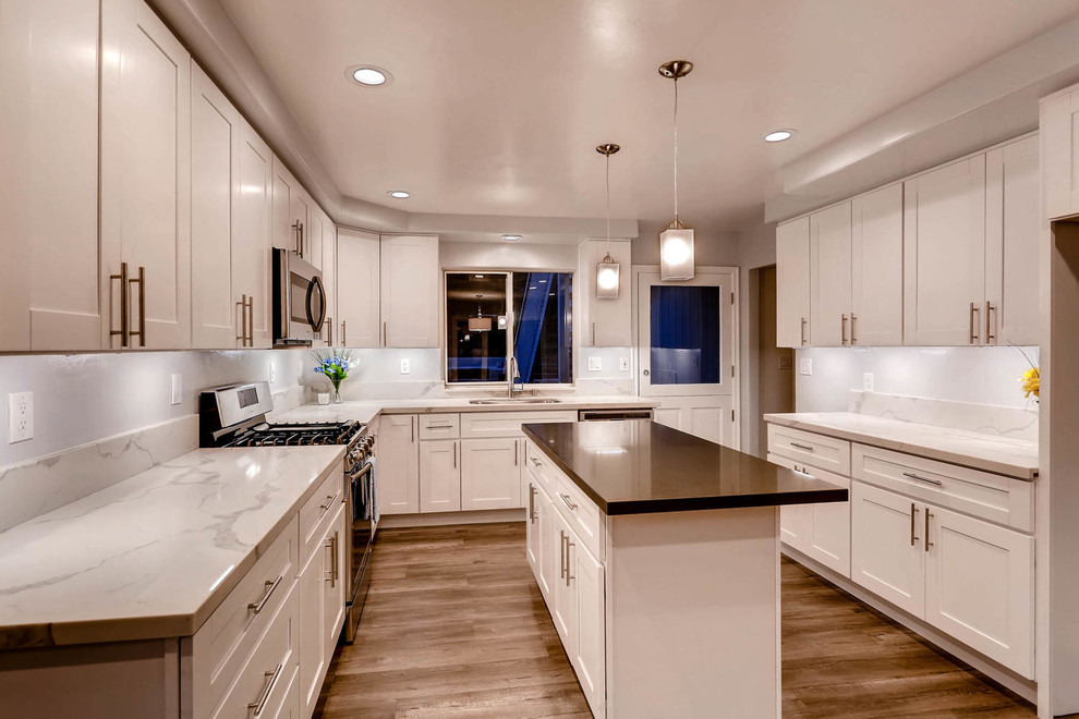 Idéer för att renovera ett mellanstort funkis kök, med en undermonterad diskho, skåp i shakerstil, vita skåp, bänkskiva i kvarts, vitt stänkskydd, stänkskydd i sten, rostfria vitvaror, ljust trägolv, en köksö och grått golv