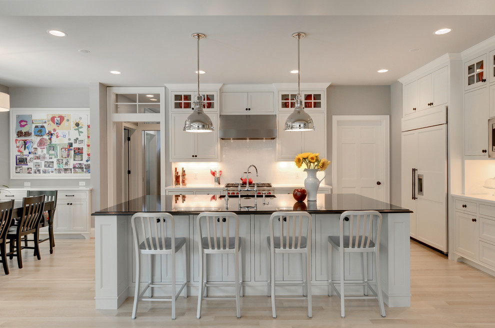 Example of a classic kitchen design in Minneapolis with recessed-panel cabinets, white cabinets, white backsplash and paneled appliances