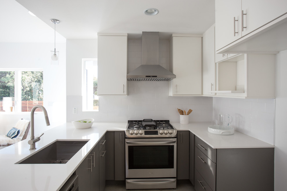This is an example of a medium sized modern u-shaped open plan kitchen in Austin with a submerged sink, flat-panel cabinets, grey cabinets, soapstone worktops, white splashback, metro tiled splashback, stainless steel appliances, concrete flooring and a breakfast bar.