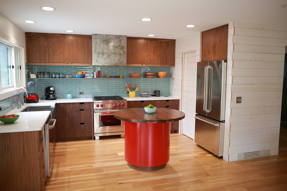 Exemple d'une cuisine moderne en bois foncé avec un évier de ferme, un placard à porte plane, un plan de travail en quartz modifié, une crédence bleue, une crédence en carreau de verre, un électroménager en acier inoxydable et un sol en bois brun.