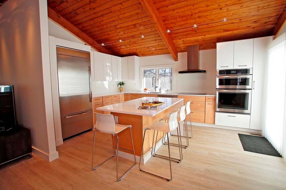 Exempel på ett stort modernt vit vitt kök, med släta luckor, rostfria vitvaror, en köksö, beiget golv, en undermonterad diskho, vita skåp, bänkskiva i kvarts, vitt stänkskydd och ljust trägolv