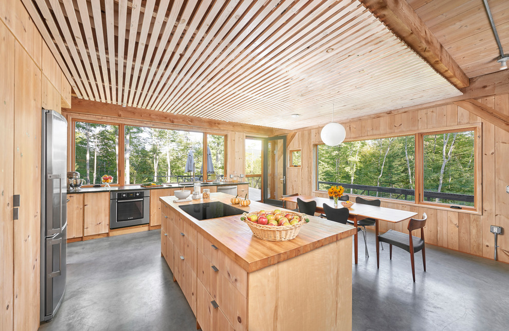 Immagine di una cucina stile rurale con ante lisce, ante in legno chiaro, top in legno, paraspruzzi a finestra, elettrodomestici in acciaio inossidabile e pavimento in cemento