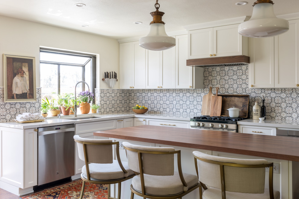 Eat-in kitchen - mid-sized transitional l-shaped medium tone wood floor and brown floor eat-in kitchen idea in San Diego with an island, brown countertops, a drop-in sink, shaker cabinets, white cabinets, wood countertops, white backsplash, marble backsplash and stainless steel appliances