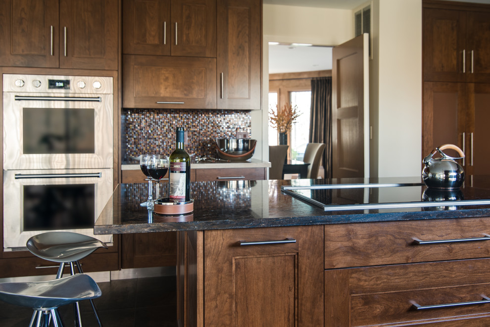 Modelo de cocina minimalista con encimera de mármol, salpicadero marrón, salpicadero de azulejos de vidrio y electrodomésticos de acero inoxidable