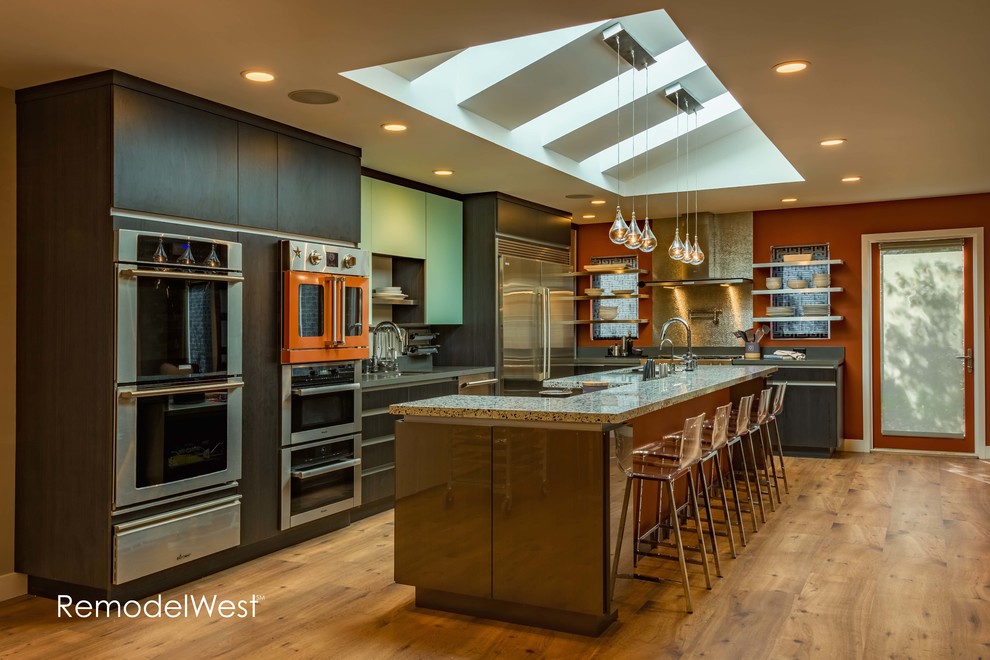 Inspiration for a medium sized modern l-shaped open plan kitchen in San Francisco with a triple-bowl sink, flat-panel cabinets, grey cabinets, engineered stone countertops, metallic splashback, stainless steel appliances, cork flooring and an island.