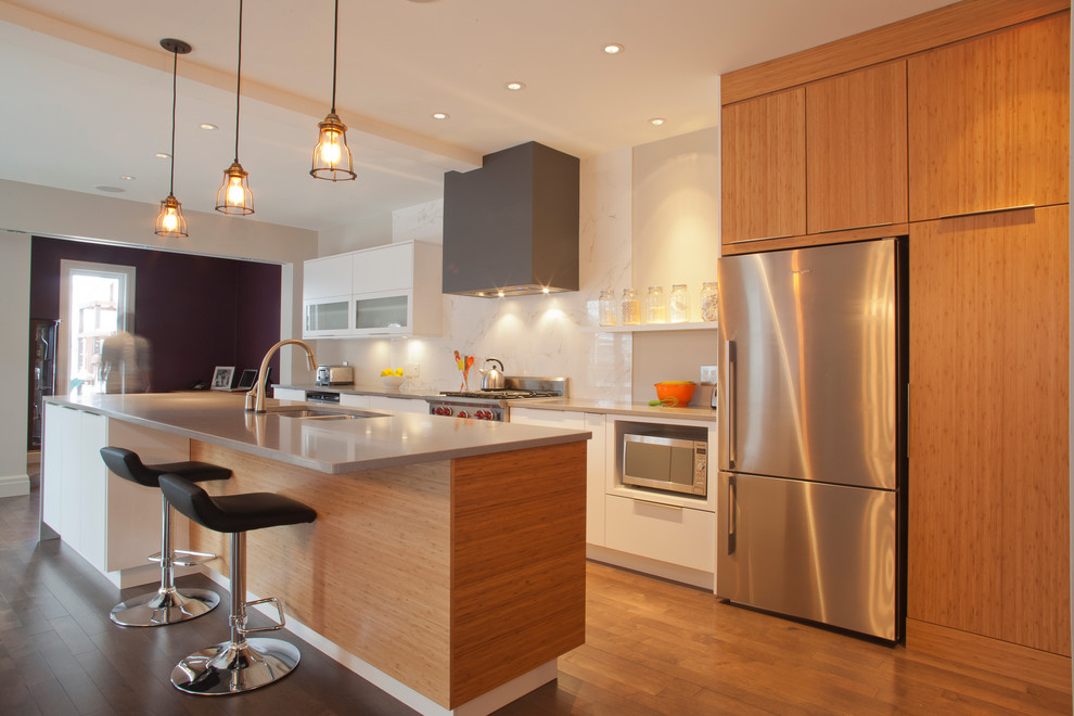 Immagine di una cucina parallela minimalista con lavello sottopiano, ante lisce, ante in legno scuro, paraspruzzi bianco, elettrodomestici in acciaio inossidabile e pavimento in legno massello medio