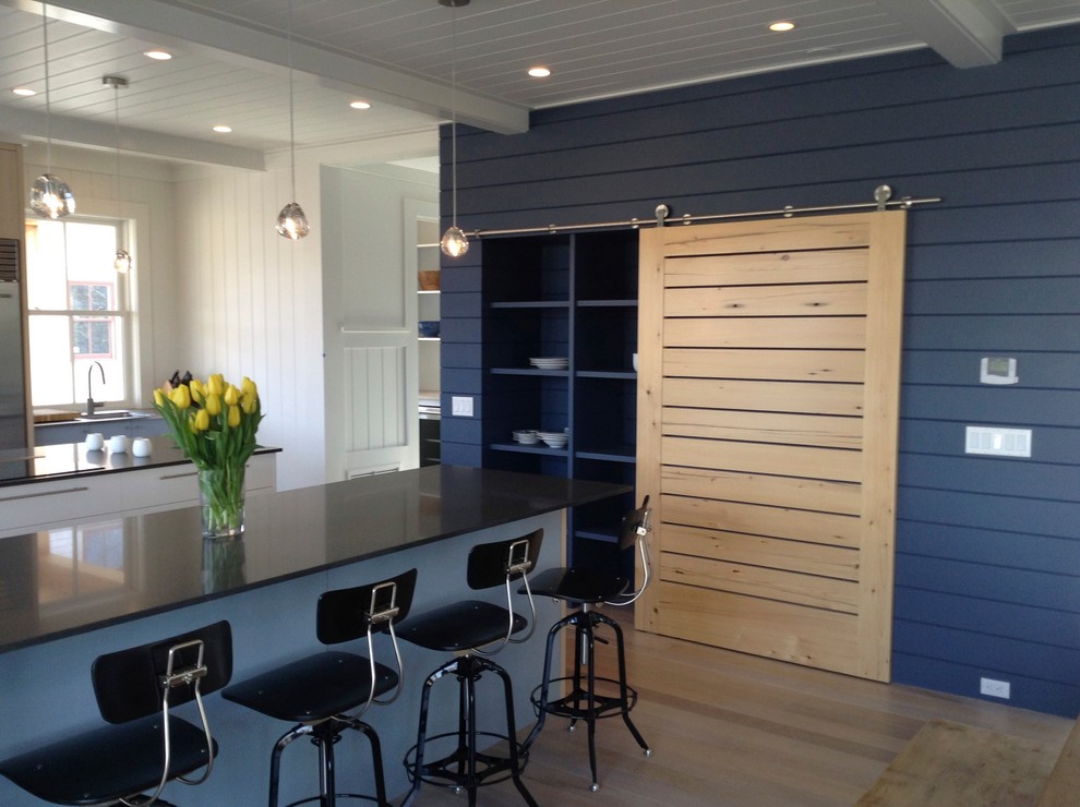 Foto di una grande cucina minimalista con lavello sottopiano, ante lisce, ante blu, elettrodomestici in acciaio inossidabile, parquet chiaro e pavimento marrone