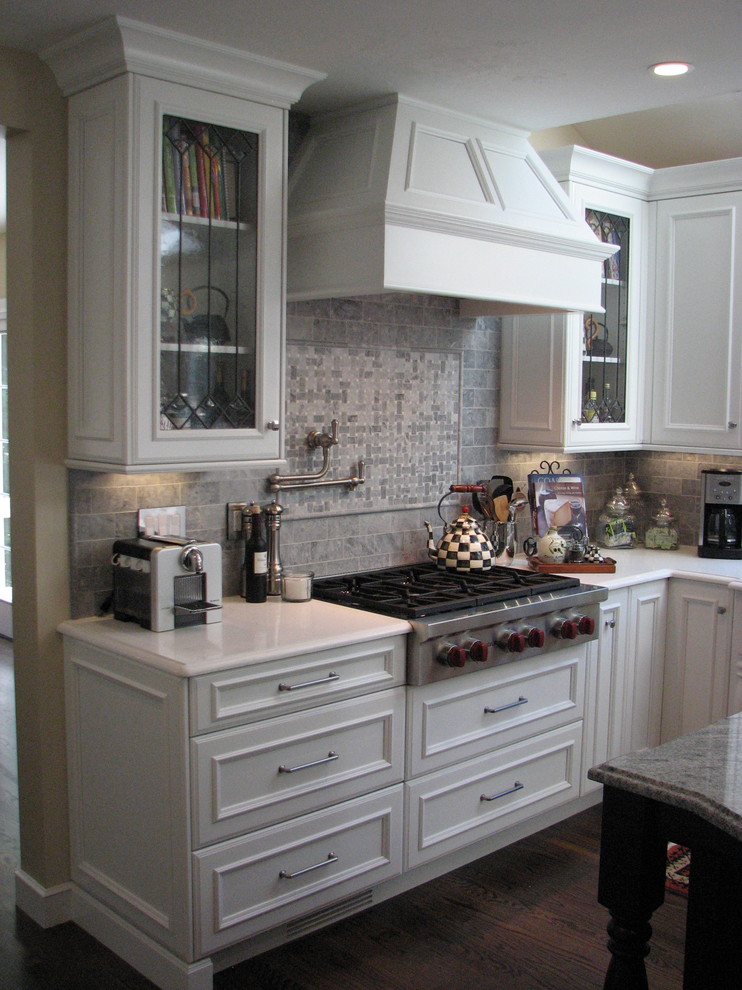 Exempel på ett mellanstort klassiskt l-kök, med en rustik diskho, luckor med infälld panel, vita skåp, bänkskiva i kvarts, grått stänkskydd, stänkskydd i stenkakel, integrerade vitvaror, mörkt trägolv och en köksö