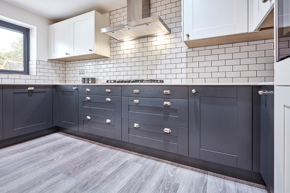 Inspiration for a mid-sized transitional u-shaped laminate floor and gray floor eat-in kitchen remodel in Other with an integrated sink, shaker cabinets, gray cabinets, quartzite countertops, white backsplash, porcelain backsplash, black appliances, an island and white countertops