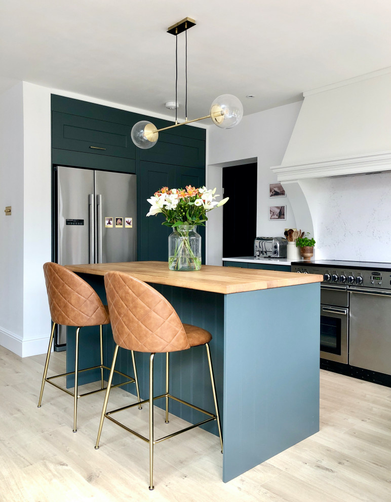 Design ideas for a medium sized modern l-shaped open plan kitchen in Other with a submerged sink, shaker cabinets, blue cabinets, wood worktops, white splashback, engineered quartz splashback, stainless steel appliances, laminate floors, an island, beige floors and brown worktops.