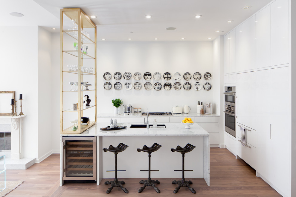 Open concept kitchen - small contemporary l-shaped medium tone wood floor and brown floor open concept kitchen idea in New York with an undermount sink, flat-panel cabinets, white cabinets, an island, marble countertops, stainless steel appliances and gray countertops
