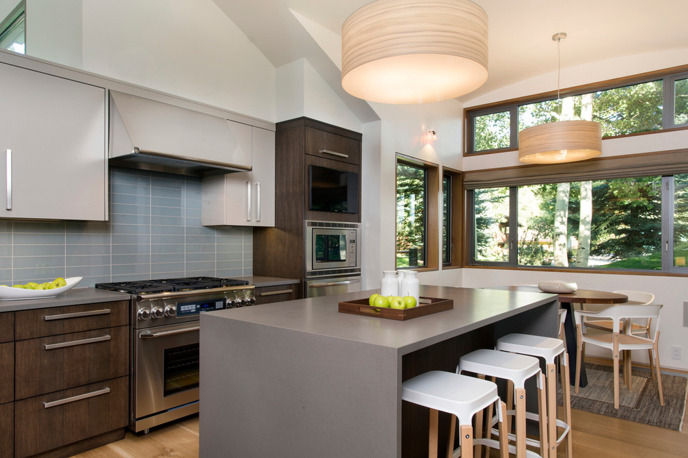 Large trendy u-shaped light wood floor and beige floor eat-in kitchen photo in Denver with flat-panel cabinets, gray cabinets, blue backsplash, glass tile backsplash, stainless steel appliances, an island, a single-bowl sink and quartz countertops