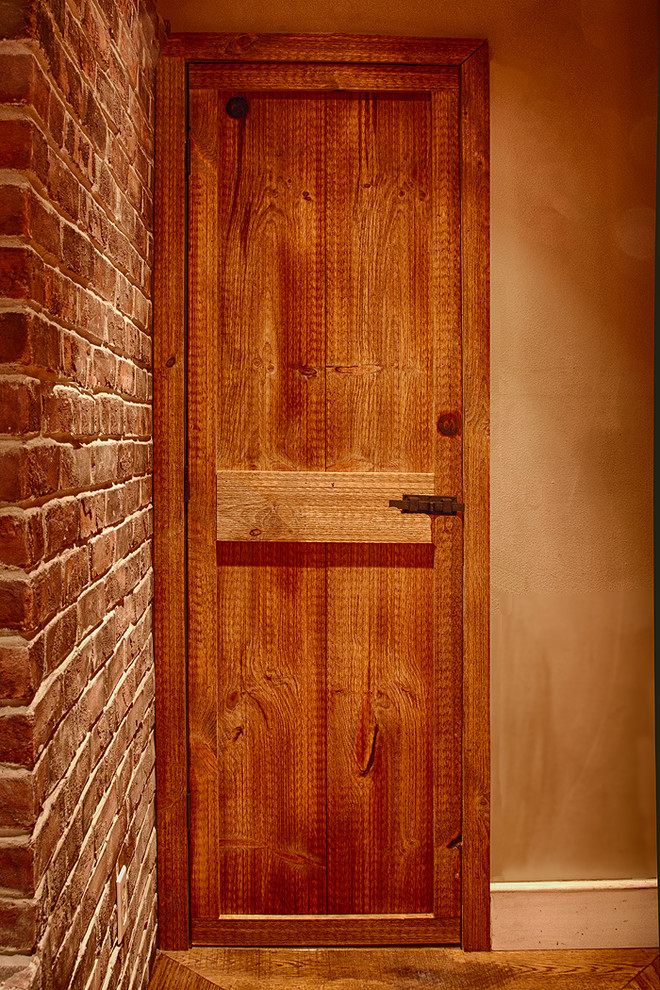 Diseño de cocina comedor campestre con fregadero bajoencimera, armarios con paneles lisos, puertas de armario de madera oscura, encimera de madera, salpicadero negro, salpicadero de azulejos de piedra y electrodomésticos de acero inoxidable