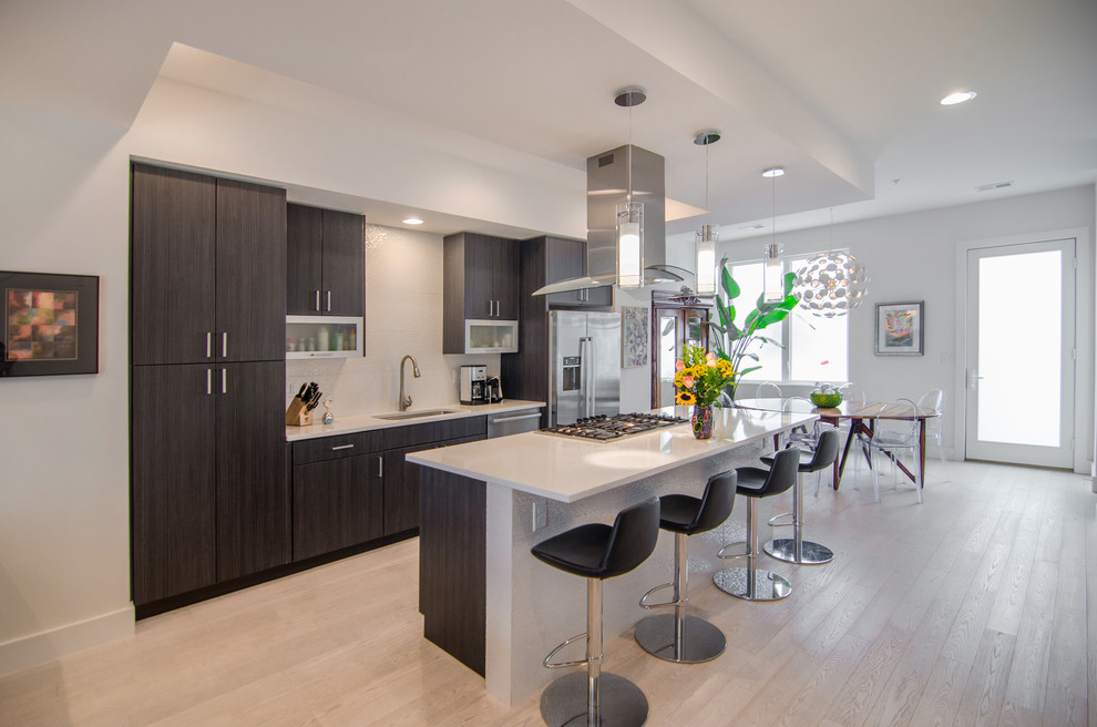 Mid-sized trendy single-wall light wood floor and white floor eat-in kitchen photo in Denver with an undermount sink, flat-panel cabinets, dark wood cabinets, quartz countertops, white backsplash, porcelain backsplash, stainless steel appliances and an island