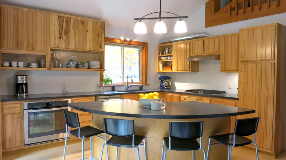 Photo of a large traditional l-shaped open plan kitchen in Minneapolis with an integrated sink, flat-panel cabinets, concrete worktops, stainless steel appliances, light hardwood flooring and an island.