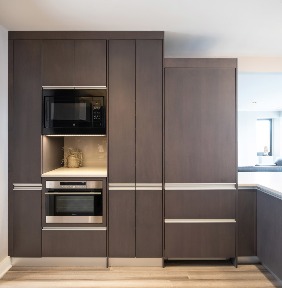 Example of a large minimalist open concept kitchen design in Kansas City with an integrated sink, glass-front cabinets, dark wood cabinets, quartz countertops, glass sheet backsplash, paneled appliances and a peninsula
