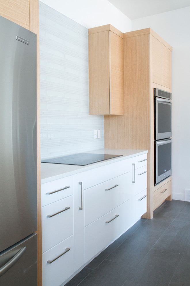 Modern inredning av ett mellanstort kök, med en undermonterad diskho, släta luckor, skåp i ljust trä, bänkskiva i kvarts, vitt stänkskydd, stänkskydd i glaskakel, rostfria vitvaror, klinkergolv i keramik och en köksö