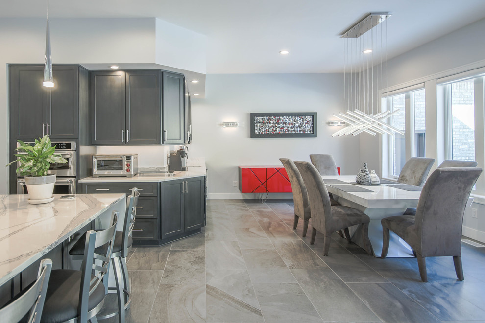 Example of a huge minimalist l-shaped porcelain tile and gray floor eat-in kitchen design in Detroit with a farmhouse sink, recessed-panel cabinets, gray cabinets, quartz countertops, white backsplash, stainless steel appliances, an island and white countertops