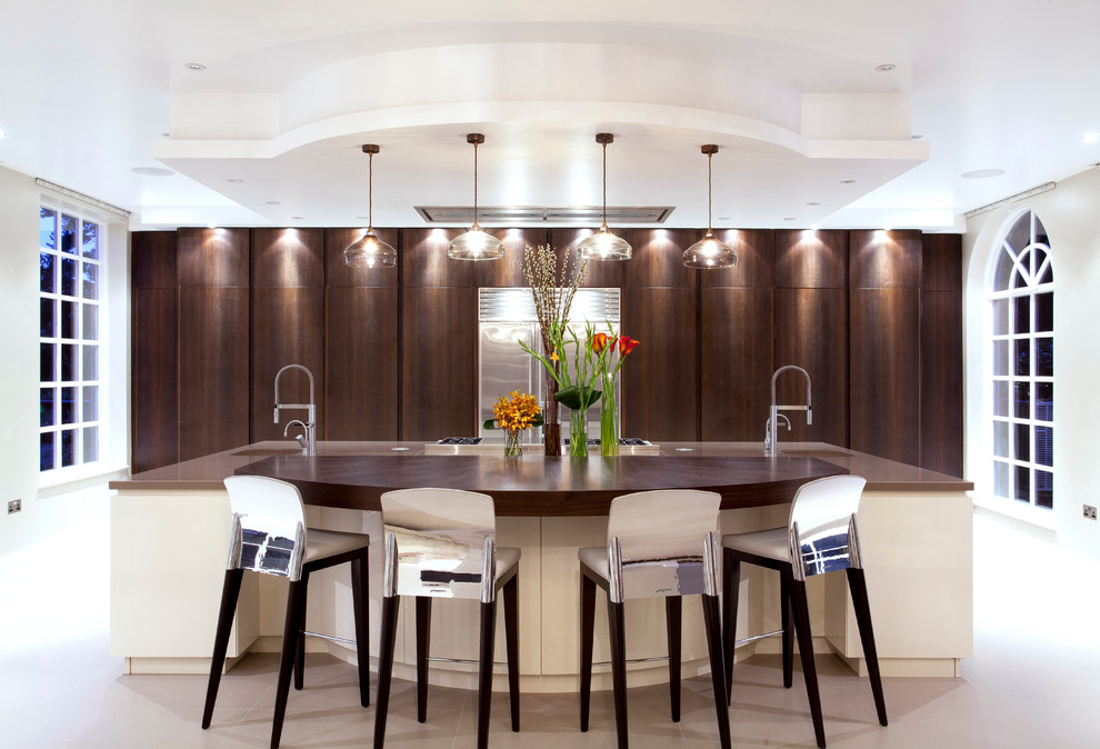 Inspiration for a large contemporary galley kitchen in London with flat-panel cabinets, dark wood cabinets, stainless steel appliances and an island.