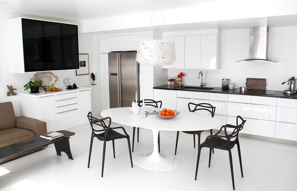 Foto på ett funkis kök med öppen planlösning, med en undermonterad diskho, släta luckor, rostfria vitvaror, bänkskiva i kvartsit, vitt stänkskydd och betonggolv