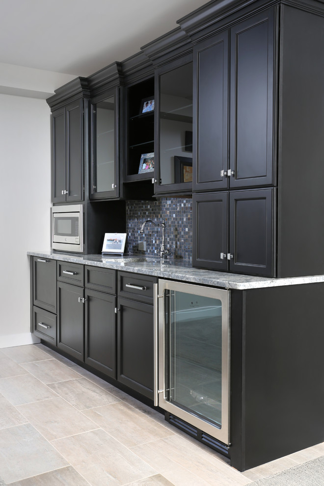 Klassisk inredning av ett stort kök, med en undermonterad diskho, luckor med upphöjd panel, svarta skåp, granitbänkskiva, blått stänkskydd, stänkskydd i stenkakel, rostfria vitvaror, marmorgolv och en köksö