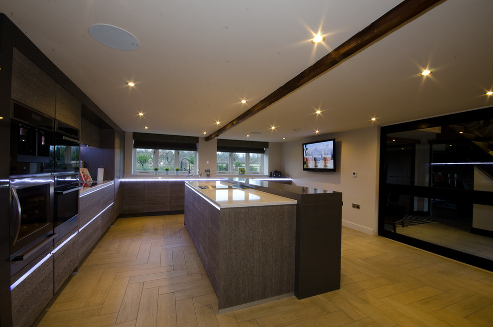Inspiration for a large contemporary l-shaped enclosed kitchen in West Midlands with a double-bowl sink, flat-panel cabinets, medium wood cabinets, composite countertops, grey splashback, glass tiled splashback, stainless steel appliances, ceramic flooring and an island.