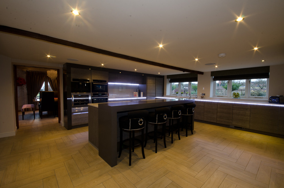 Photo of a large contemporary grey and cream l-shaped enclosed kitchen in West Midlands with a double-bowl sink, flat-panel cabinets, medium wood cabinets, composite countertops, grey splashback, glass tiled splashback, stainless steel appliances, ceramic flooring and an island.