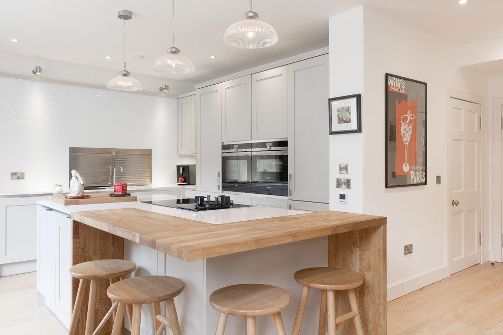 Стильный дизайн: угловая кухня-гостиная среднего размера в современном стиле с серыми фасадами, техникой из нержавеющей стали, островом, фасадами с утопленной филенкой, светлым паркетным полом и бежевым полом - последний тренд