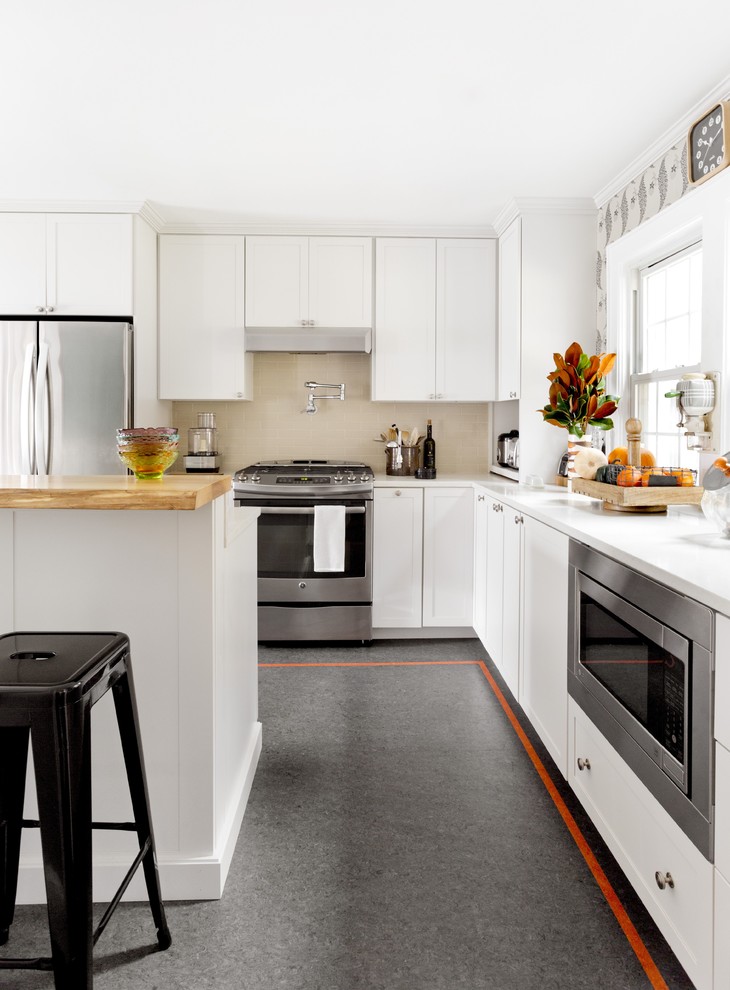Ejemplo de cocina contemporánea con armarios con paneles empotrados, puertas de armario blancas, salpicadero beige, electrodomésticos de acero inoxidable y una isla