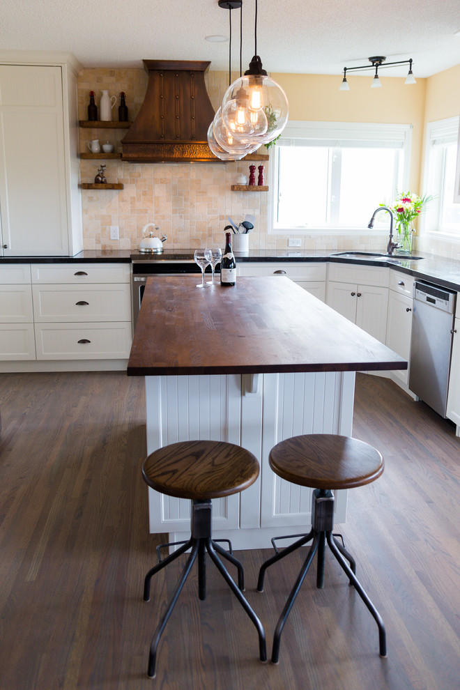 Eat-in kitchen - mid-sized rustic l-shaped medium tone wood floor and brown floor eat-in kitchen idea in Calgary with an undermount sink, flat-panel cabinets, white cabinets, granite countertops, beige backsplash, stone tile backsplash, stainless steel appliances and an island