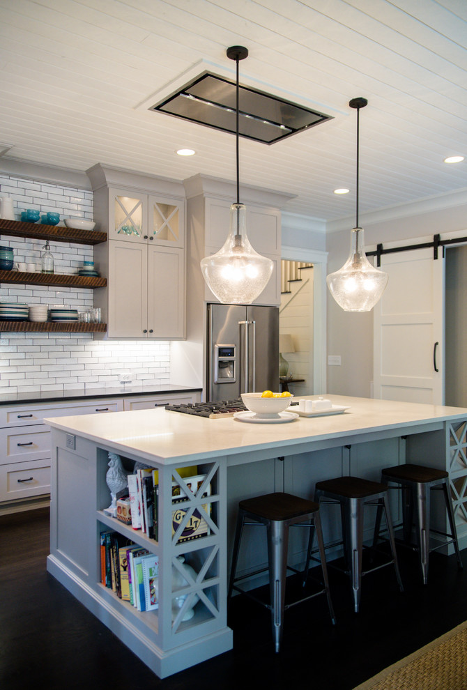 Photo of a large rural grey and white l-shaped kitchen in Atlanta with shaker cabinets, grey cabinets, white splashback, metro tiled splashback, stainless steel appliances, dark hardwood flooring, brown floors, engineered stone countertops and an island.