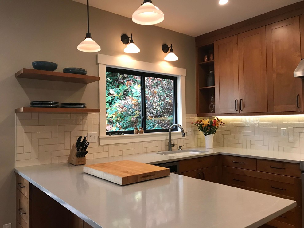 Inredning av ett amerikanskt mellanstort grå grått kök, med en undermonterad diskho, skåp i shakerstil, skåp i mellenmörkt trä, bänkskiva i kvarts, vitt stänkskydd, stänkskydd i keramik, rostfria vitvaror, mellanmörkt trägolv, en halv köksö och brunt golv