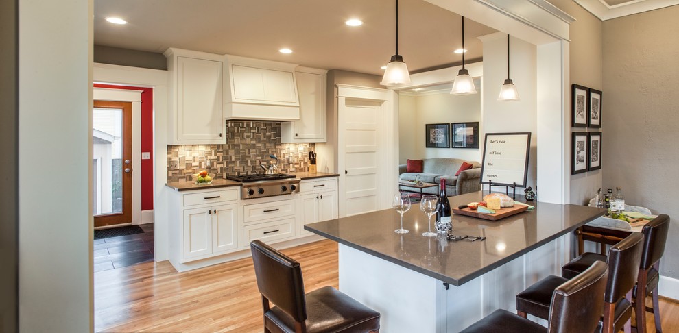 Eat-in kitchen - mid-sized craftsman u-shaped medium tone wood floor eat-in kitchen idea in Portland with white cabinets, gray backsplash, glass tile backsplash, stainless steel appliances, a peninsula, an undermount sink, shaker cabinets and soapstone countertops