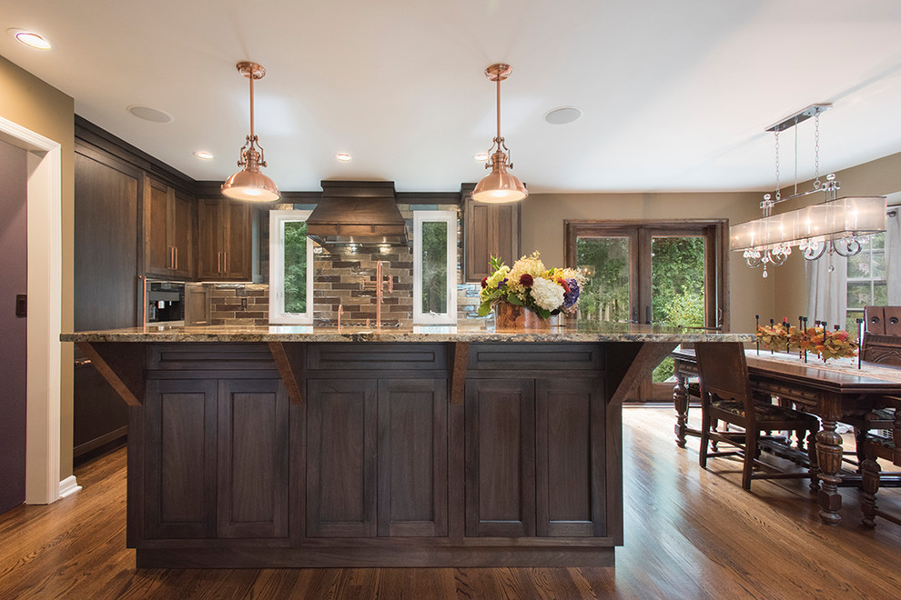 Exempel på ett mellanstort klassiskt kök, med en rustik diskho, luckor med infälld panel, bruna skåp, granitbänkskiva, rostfria vitvaror, mörkt trägolv, en köksö och brunt golv