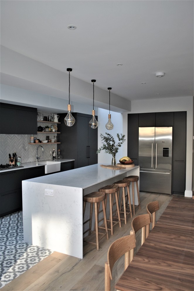 Inspiration for a contemporary kitchen/diner in London with a belfast sink, flat-panel cabinets, grey cabinets, quartz worktops, white splashback, metro tiled splashback, ceramic flooring and multi-coloured floors.