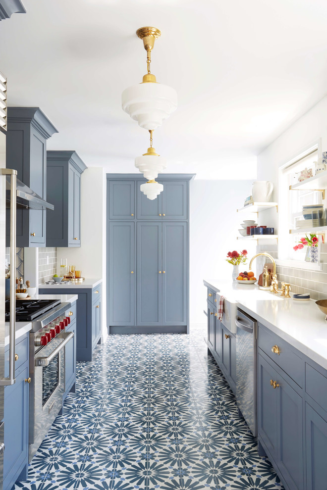 Example of a transitional l-shaped multicolored floor kitchen design in San Francisco with a farmhouse sink, shaker cabinets, blue cabinets, gray backsplash, subway tile backsplash and stainless steel appliances