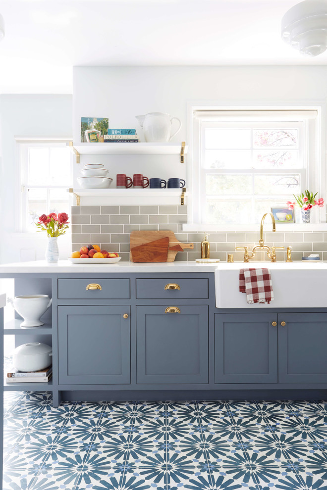 Cette image montre une cuisine américaine parallèle traditionnelle de taille moyenne avec un placard avec porte à panneau encastré, des portes de placard bleues et aucun îlot.