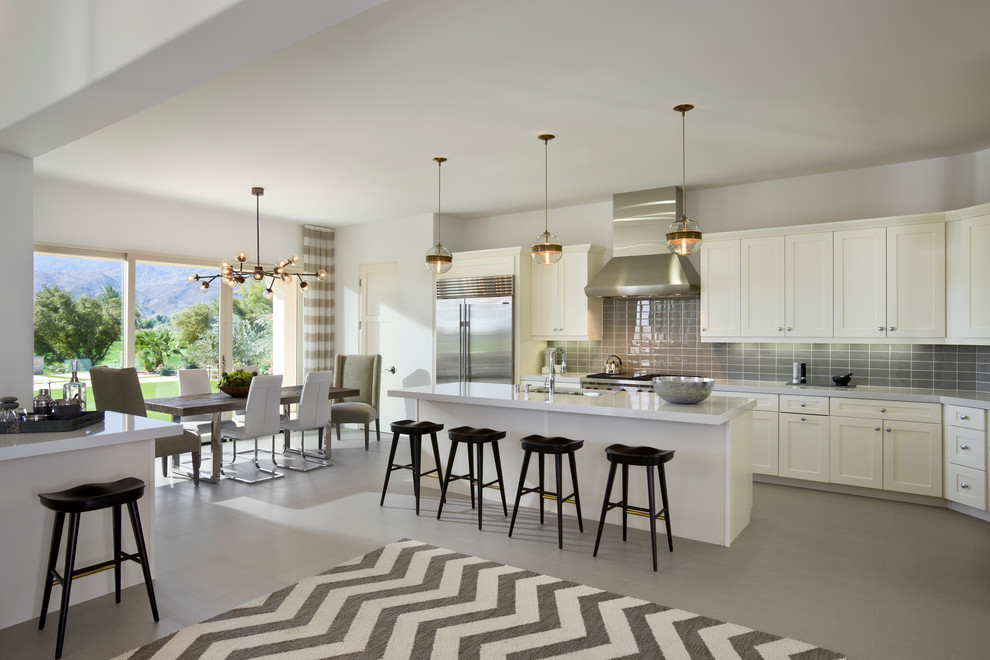 Traditional grey and white l-shaped open plan kitchen in Orange County with shaker cabinets, white cabinets, grey splashback, metro tiled splashback, stainless steel appliances and an island.