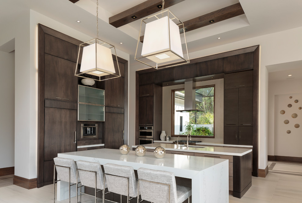 Example of a large minimalist l-shaped porcelain tile and beige floor kitchen design in Miami with flat-panel cabinets, dark wood cabinets, paneled appliances, two islands, white countertops and an undermount sink